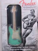 Fender Stratocaster-shaped silver coin in packaging with a black and white image of a man playing guitar.